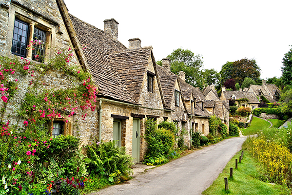 Charming stone cottages lined along a picturesque pathway, adorned with vibrant flowers and lush greenery, showcasing the beauty of countryside architecture.